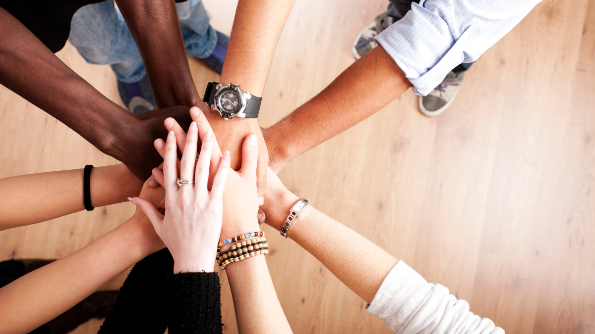 Team of professionals standing in a circle with their hands on top of each other